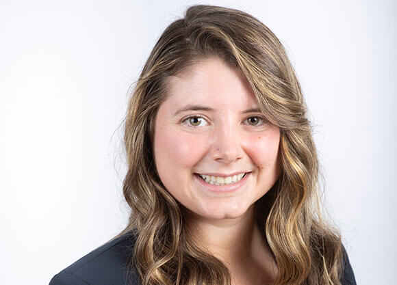 Gabrielle Donofrio poses smiling in front of a gray background