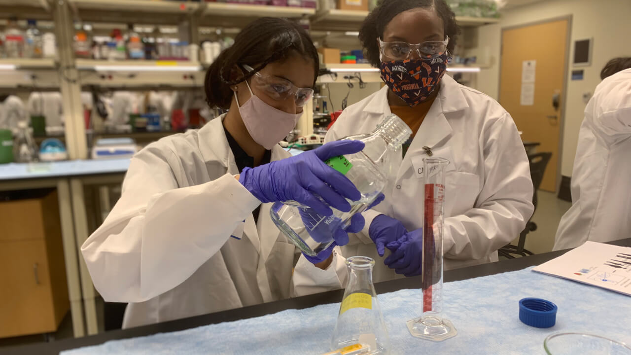 A student conducts a science experiment with teacher supervision.