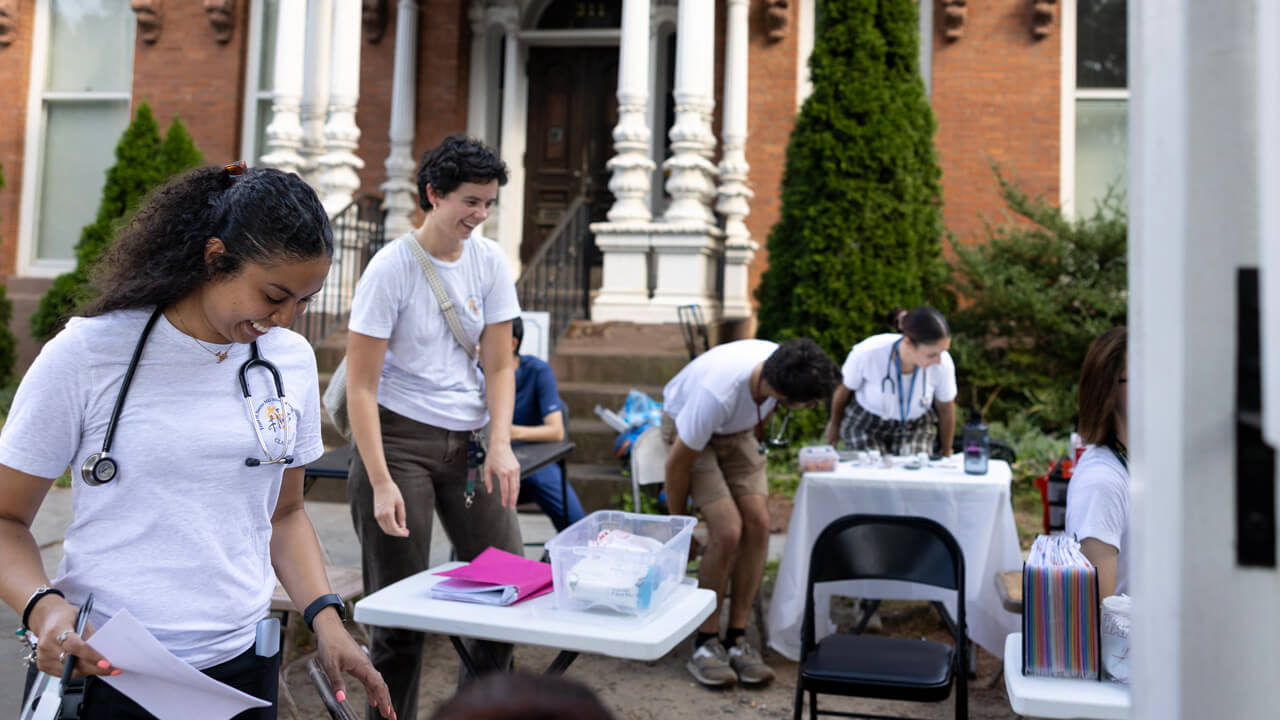 2 female medical students performing health assessments while running a street health clinic