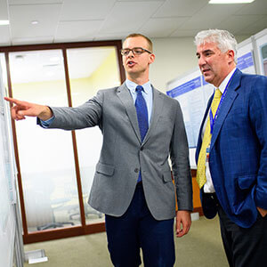 Dr. Richard Salzano Jr. looks at a poster his student mentee made during a presentation