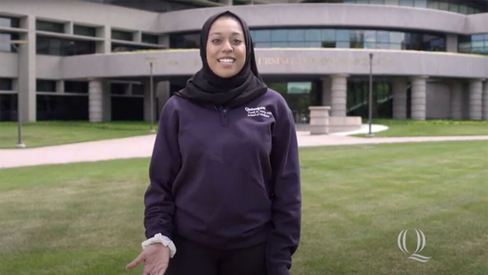 A student stands outside the Center for Medicine, Nursing and Health Sciences, starts video